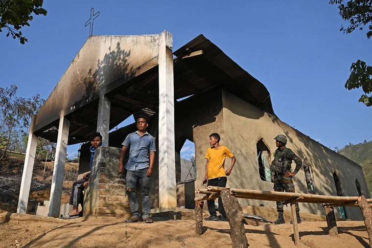 Um soldado do exército indiano (R) está junto com aldeões em frente a uma igreja saqueada que foi incendiada por uma multidão na área atingida pela violência étnica da aldeia de Heiroklian, no distrito de Senapati, no estado indiano de Manipur, em 8 de maio de 2023. Cerca de 23.000 pessoas fugiram dos distúrbios que eclodiram na semana passada no estado montanhoso do nordeste que faz fronteira com Mianmar. Os últimos confrontos eclodiram entre a maioria do povo Meitei, que é majoritariamente hindu, que vive dentro e ao redor da capital de Manipur, Imphal, e a tribo Kuki das colinas, de maioria cristã. | ARUN SANKAR/AFP via Getty Images