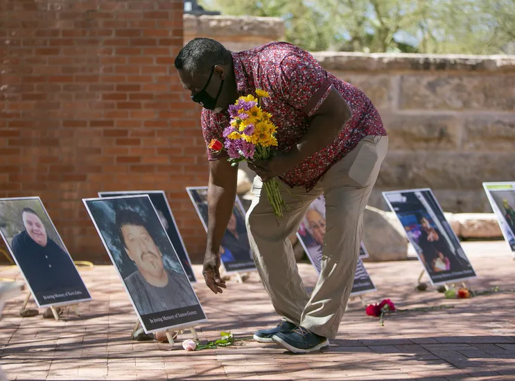 Todd Bailey coloca flores na frente de fotos de pessoas que morreram devido ao COVID-19 no Arizona Heritage Center no Papago Park em Tempe, Arizona, em 1º de março de 2021.
Meg Potter, A República via USA TODAY NETWORK